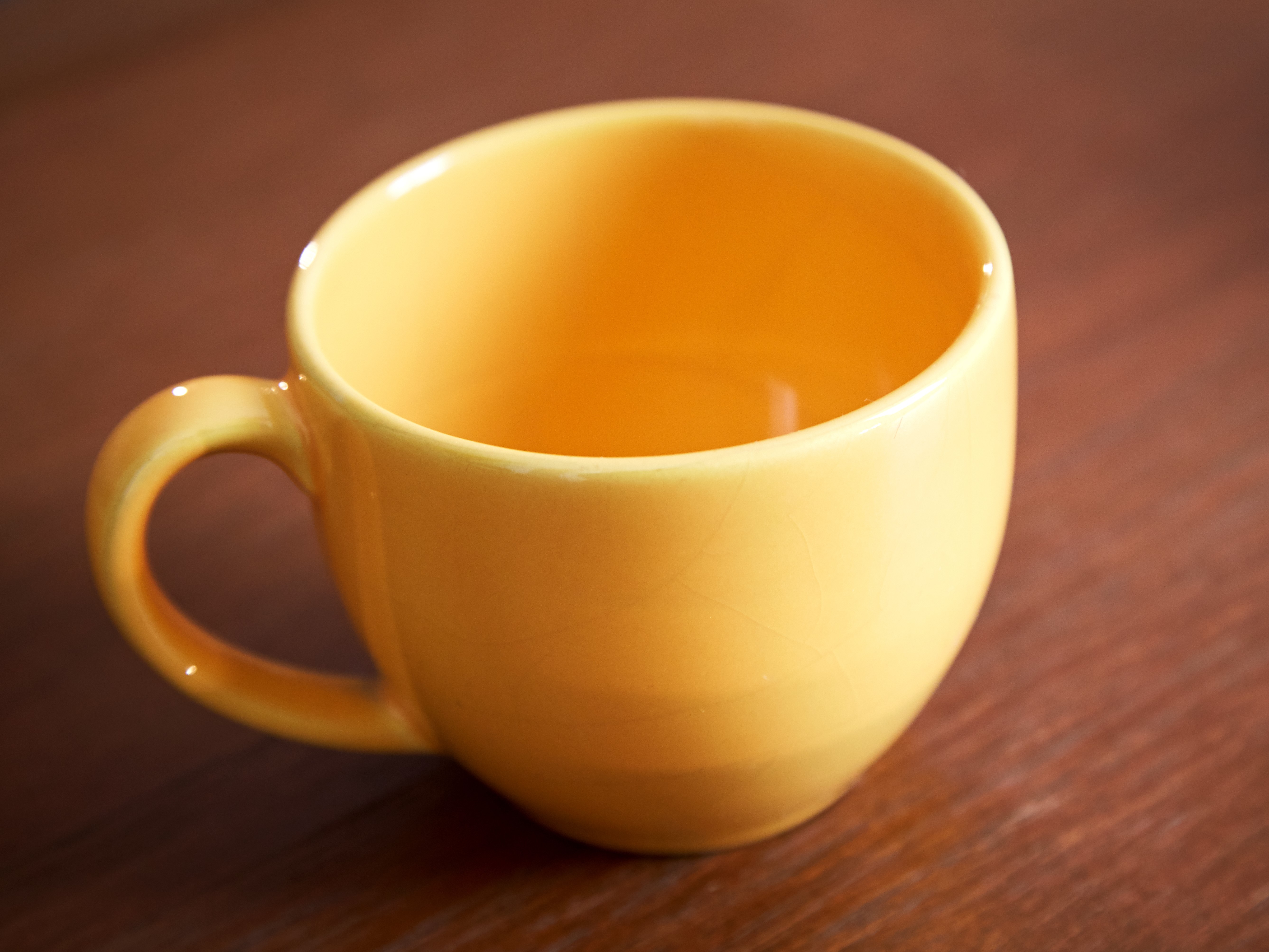 empty, ceramic yellow mug on wood table